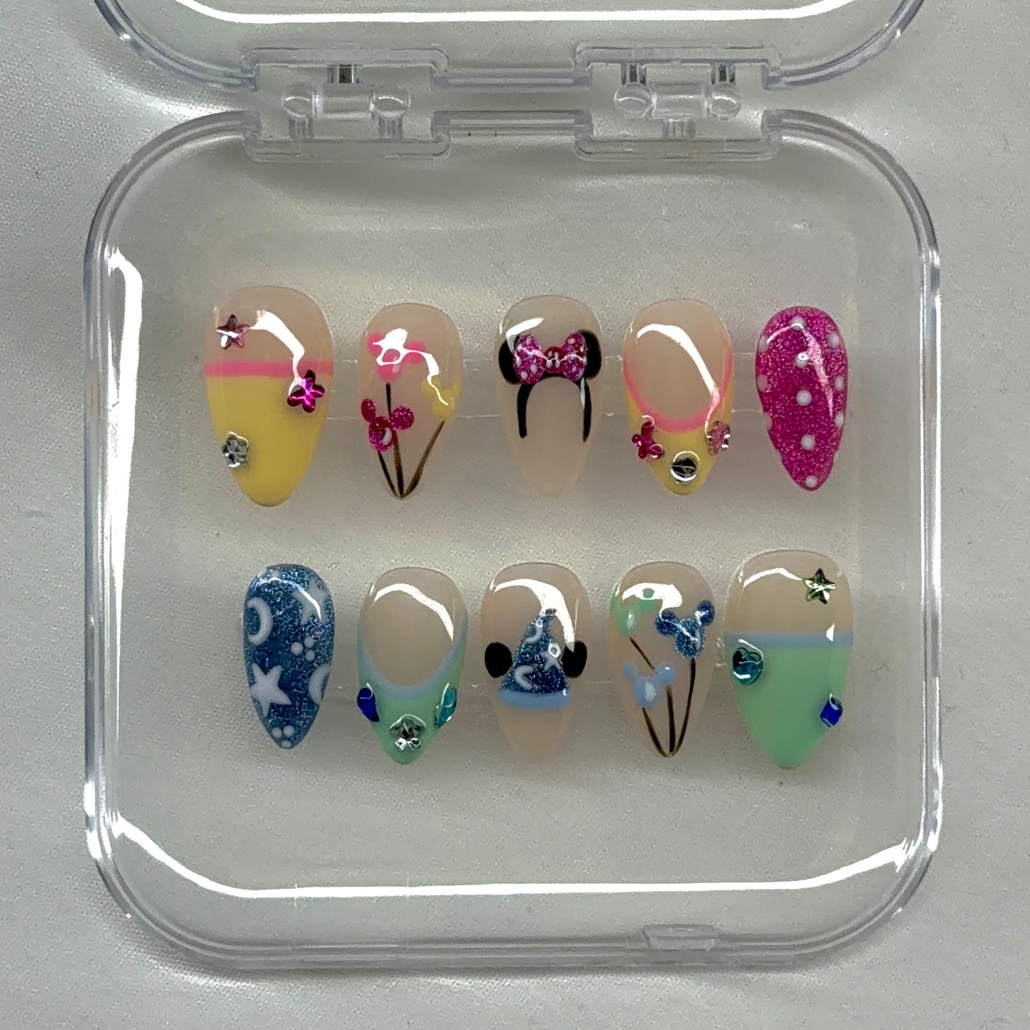 A playful Disney-inspired luxe set featuring glitter details, iconic silhouettes, pastel tones, bows, and whimsical mixed nail art